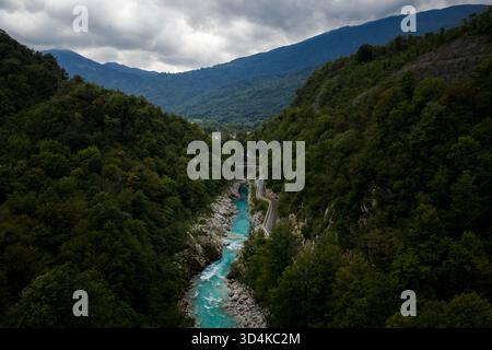 Vue aérienne de la rivière Teal Soca sculpte un chemin à travers les forêts denses et vert foncé près de Kobarid, niché sous les montagnes majestueuses, Kobarid, Banque D'Images