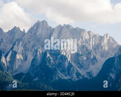 Vue aérienne des pics déchiquetés et ensoleillés s'élèvent majestueusement, projetant des ombres sur les pentes verdoyantes en contrebas, une symphonie de lumière et d'ombre dans la nature gra Banque D'Images