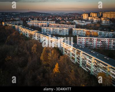 Vue aérienne de longs blocs d'appartements descendant une pente boisée, leurs balcons attrapant la lueur chaude du soleil couchant, quartier Suchanino, Banque D'Images