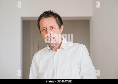 Homme d'affaires mature fatigué avec le visage non rasé regardant la caméra dans l'intérieur du bureau. Mise au point sélective. Banque D'Images