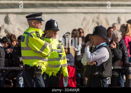 Des policiers en vestes haute visibilité montent la garde lors d'un événement public au milieu d'une foule curieuse Banque D'Images