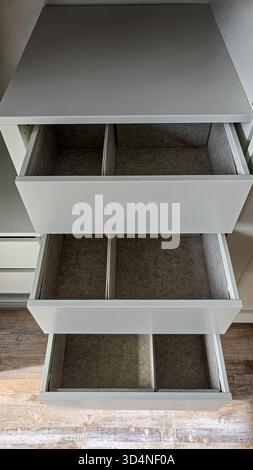 Vue de dessus des tiroirs ouverts avec des organisateurs gris intégrés dans une armoire blanche. Tri et organisation Banque D'Images