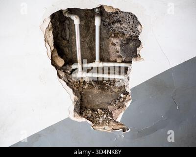 vue de nouvelles conduites d'eau en plastique dans le mur cassé de l'ancien immeuble d'appartements Banque D'Images