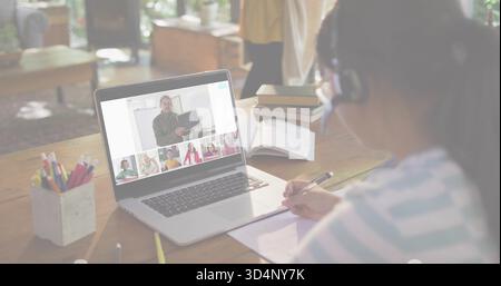 Prise de notes fille portant casque, dessus rayé, étude à la maison avec ordinateur portable et ordinateur portable, espace de copie Banque D'Images