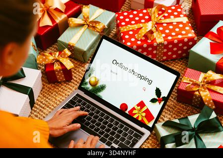 Femme utilisant un ordinateur portable avec signe sur l'écran achats en ligne et cadeaux de Noël sur le sol. Banque D'Images