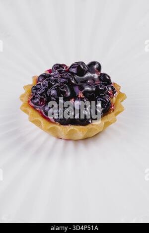 Nourriture, tarte aux myrtilles fraîchement cuite suintant de baies juteuses, présentée sur une surface blanche immaculée Banque D'Images