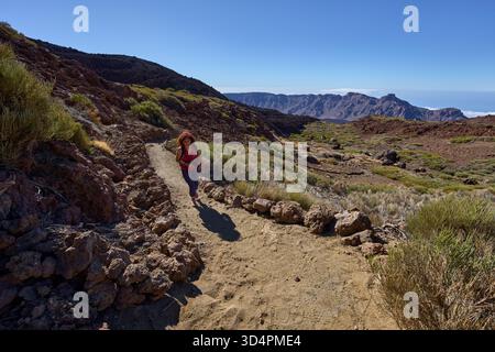 Femme photographe et randonneur marchant en montée sur un sentier vers Pico Viejo avec la caldera Las Cañadas en arrière-plan Banque D'Images