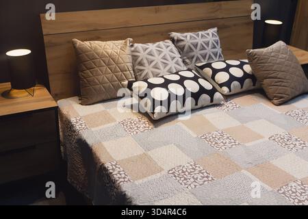 Oreillers colorés disposés sur un lit soigneusement fait dans un cadre de chambre confortable. Intérieur Banque D'Images