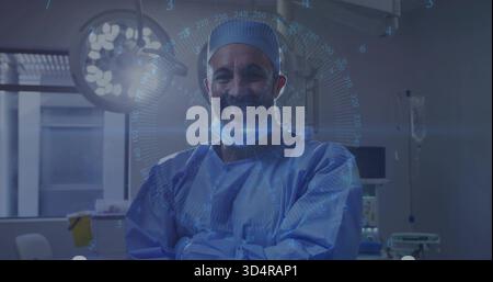 Chirurgien masculin debout portant une blouse chirurgicale bleue, les bras croisés dans LE BLOC OPÉRATOIRE, le HUD brillant, la lumière chirurgicale Banque D'Images