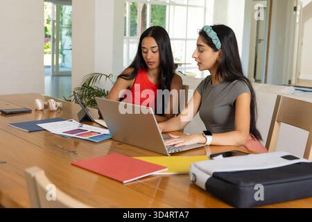 Travaillant diverses amies féminines examinant la tablette et tapant sur ordinateur portable à la table en bois, avec des graphiques Banque D'Images