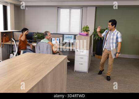 Agitant l'homme indien asiatique entrant dans le bureau ouvert sur la droite, avec ordinateur portable et tapis de yoga, espace de copie Banque D'Images