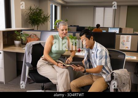 Divers collègues collaborent dans un bureau moderne ouvert, avec ordinateur portable et tablette Banque D'Images