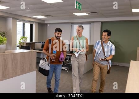 Marcher divers collègues portant tapis de yoga, bouteille d'eau et carnet dans le couloir du bureau Banque D'Images