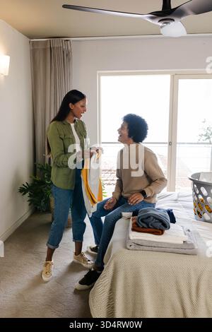 Linge pliant divers couples triant des vêtements sur le lit dans la chambre, avec chandails et panier à linge Banque D'Images