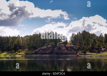 Arbres verts et rochers rouges à côté du lac au parc d'État Keyhole un jour de printemps dans le Wyoming. Banque D'Images
