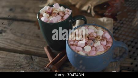 Assis mugs bleu vert cuire le cacao à la vapeur sur une table en bois, avec des guimauves roses et des bâtonnets de cannelle Banque D'Images