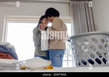 Divers vêtements pliants de couple dans le coin buanderie lumineux de la chambre, avec pile de linge et panier Banque D'Images