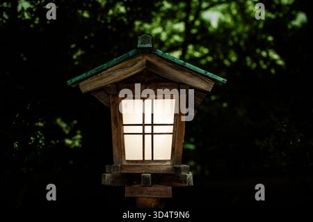 Lanterne traditionnelle en bois qui brille la nuit dans le jardin Kenrokuen, Japon. Banque D'Images