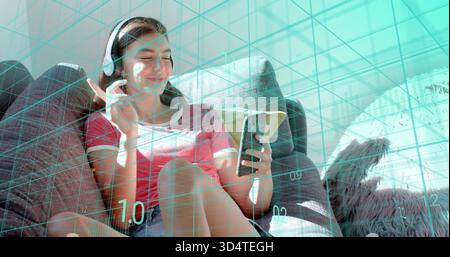 Femme souriante en chemise rouge-blanche ajustant les écouteurs tenant le téléphone sur le canapé à la maison, recouvrement sarcelle Banque D'Images