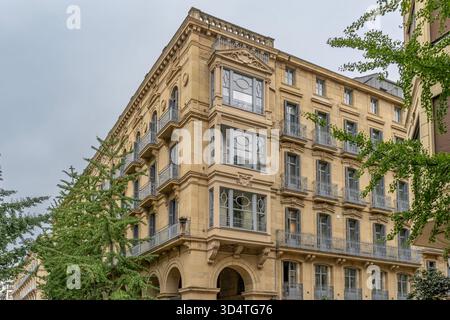 Élégant immeuble historique avec façade en pierre beige, balcons ornementaux, fenêtres cintrées, détails décoratifs, architecture urbaine Banque D'Images