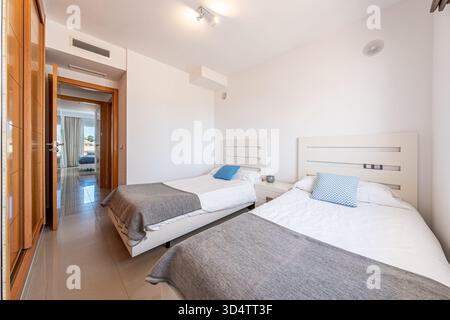 Deux lits simples dans une chambre blanche lumineuse avec placards en bois dans un appartement de vacances Banque D'Images