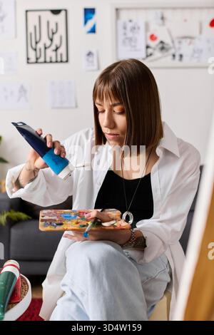 Jeune femme exprime sa créativité à la maison en concevant une pièce artistique avec concentration et soin. Banque D'Images