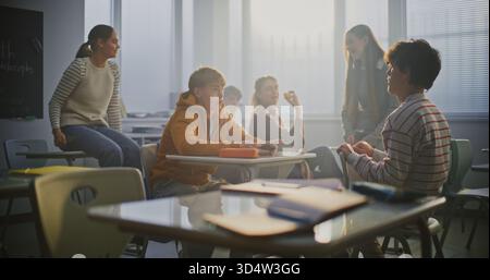 Deux étudiants masculins luttent au bureau pendant la pause, entourés de camarades de classe qui encouragent et filment sur smartphone. Concept de l'énergie des jeunes, de la compétition, de l'amitié et de l'interaction sociale. Tir statique. Banque D'Images