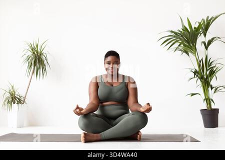 Femme noire de taille supérieure profite de la séance de yoga matinale dans Home Studio Banque D'Images