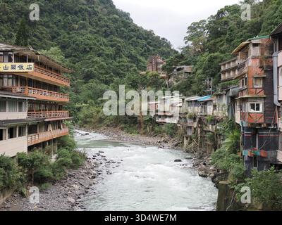 Wulai, New Taipei City, Taiwan - 14 novembre 2024 : la rivière Nanshi coule entre les hôtels et les résidences dans le quartier montagneux des sources chaudes de Wulai. Banque D'Images