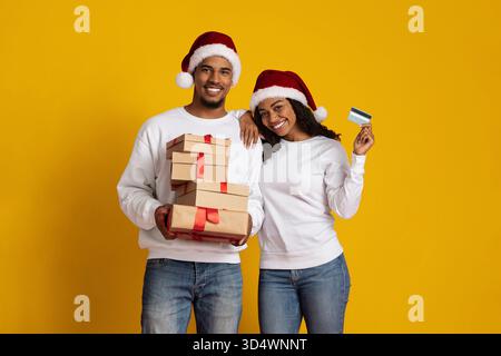 Les acheteurs des fêtes célèbrent avec des cadeaux et des chapeaux de fête dans un cadre lumineux Banque D'Images