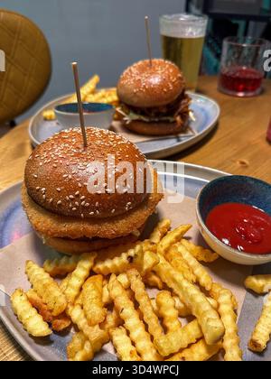Deux délicieux hamburgers avec frites froissées croustillantes et ketchup sur une table rustique en bois dans un cadre de restaurant décontracté, parfait pour un repas satisfaisant Banque D'Images
