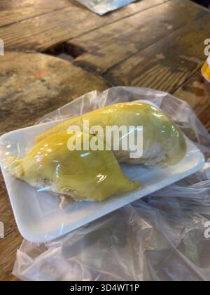 Laissez-vous tenter par la texture riche et crémeuse du durian pré-emballé, une délicatesse exotique d'Asie du Sud-est. Ces succulents segments dorés reposent sur une rouille Banque D'Images