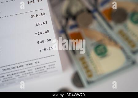 Gros plan flou des billets en dollars et reçu imprimé indiquant les calculs, les taxes et les finances personnelles Banque D'Images