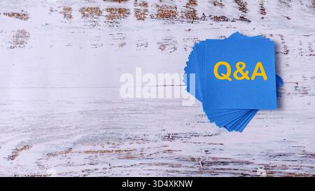 Questions et réponses : pile de notes bleues avec texte Q&R sur fond de bois Banque D'Images