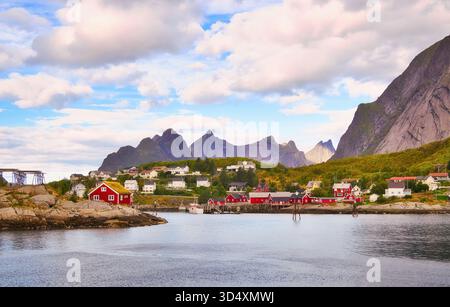 Reine dans les îles Lofoten de Norvège, avec ses montagnes vertigineuses, ses maisons traditionnelles rouges typiques et ses casiers à poissons. Banque D'Images