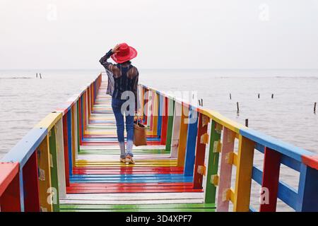 Femme dans Red Hat marchant sur Rainbow Wooden Bridge Banque D'Images