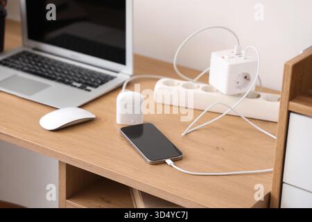 Rallonge avec téléphone mobile de charge et écouteurs sur le bureau dans le bureau Banque D'Images