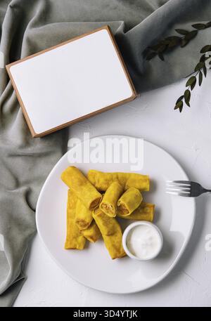 Nourriture, vue de dessus de savoureux rouleaux de printemps sur une assiette avec de la sauce et un livre de menu vide, prêt pour votre texte Banque D'Images