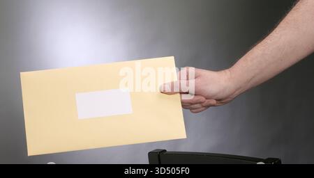 Bras et main de l'homme caucassien tenant l'enveloppe jaune, USA Banque D'Images