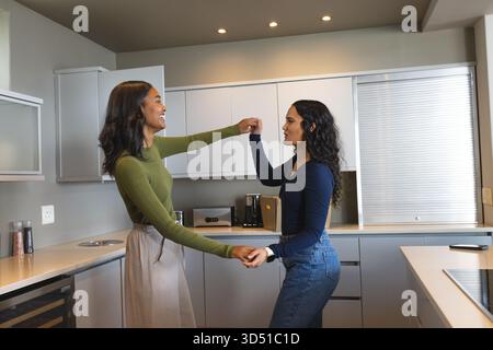 Danser diverses amies féminines filant dans une cuisine moderne, avec grille-pain et smartphone Banque D'Images
