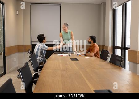 Serrant la main divers collègues se réunissant autour d'une table de conférence en bois au bureau, avec des cahiers Banque D'Images