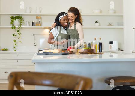 Guide mère et fille adulte coupant le poivron rouge sur l'îlot de cuisine, avec le couteau du chef Banque D'Images