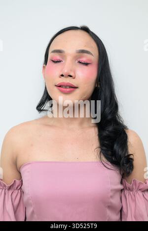 Portrait studio d'un jeune transgenre thaïlandais avec maquillage et cheveux longs. Concept d'expression de genre, fierté LGBTQ et inclusivité montrant un Banque D'Images