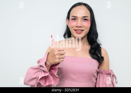Portrait studio d'un jeune transgenre thaïlandais avec maquillage et cheveux longs. Concept d'expression de genre, fierté LGBTQ et inclusivité montrant un Banque D'Images