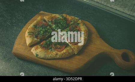 Pizza maison au fromage fraîche au four avec garniture aux herbes sur une planche de bois naturel Banque D'Images