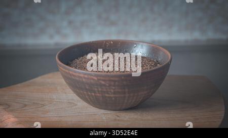 Assiette en faïence avec des céréales de sarrasin chaudes sur une table de cuisine, textures naturelles et lumière douce du soleil soulignant la simplicité réconfortante de l'homema Banque D'Images