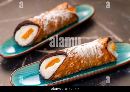 Cannoli fourrés à la ricotta sucrée saupoudrés de sucre en poudre et d'écorces d'orange confites Banque D'Images