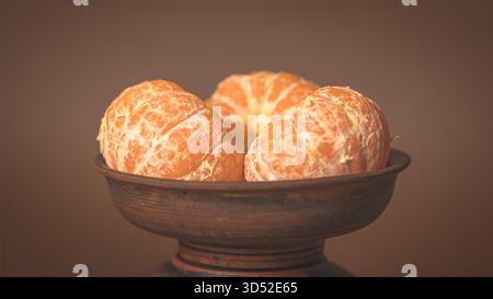 Segments de mandarines fraîchement pelées dans une plaque d'argile brune, couleur orange vibrante, scène de cuisine confortable Banque D'Images