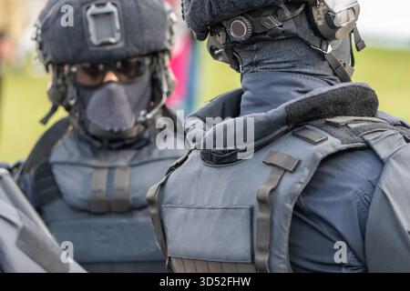 les policiers font partie d'une foule de personnes en équipement avec des casques et des masques sur le visage Banque D'Images