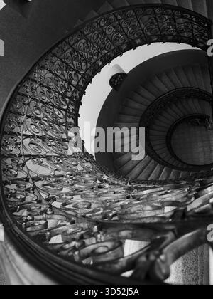 La vue aérienne de l'escalier en colimaçon monochrome montre des marches décoratives de garde-corps en fer qui créent une profondeur et une symétrie spectaculaires Banque D'Images